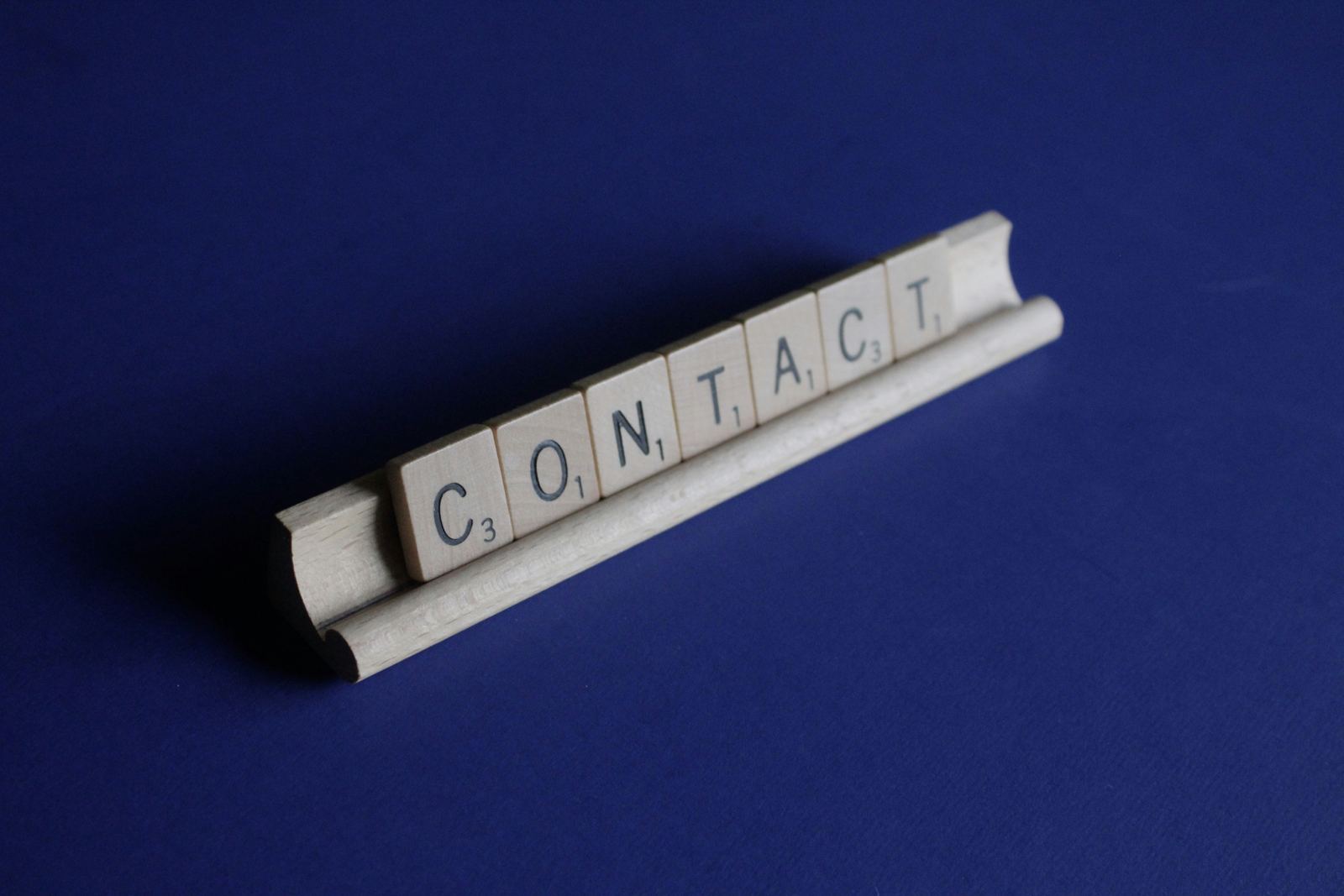 CONTACT spelled out in scrabble tiles